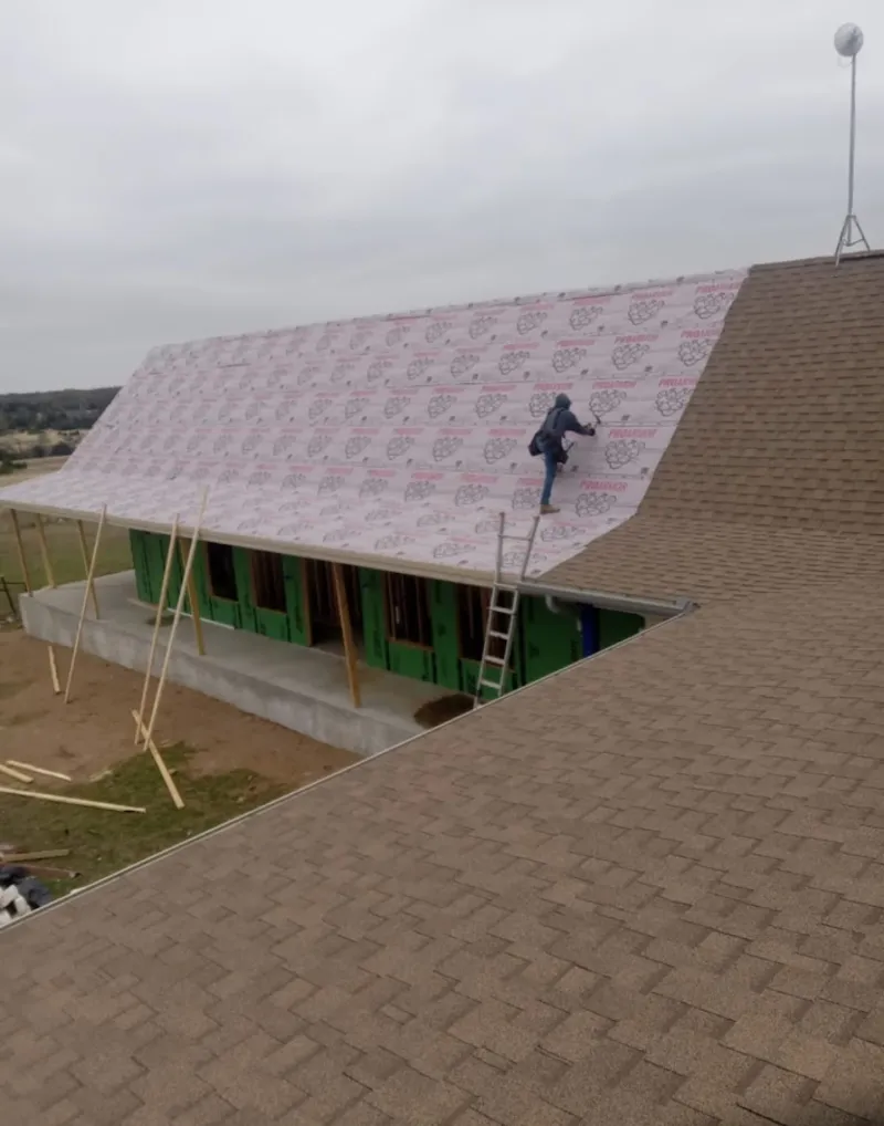 Worker preparing underlayment for a metal roof installation in Fresno